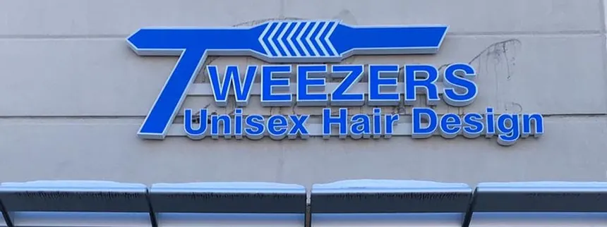 The blue Tweezers Unisex Hair Design sign above the shop front.