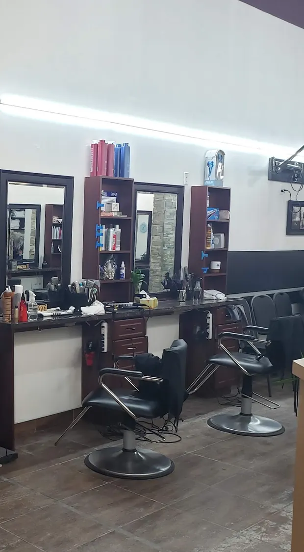 Dark-wood styling stations with mirrors and black leather chairs along a white wall.